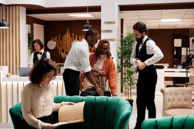 Hotelconcierge hilft den Gästen in der Lobby, hilft bei der Check-in-Prozess an der Rezeption, Bellboy trägt Trolley-Taschen und Gepäck ins Zimmer und bietet luxuriösen Service in einem modernen Resort.