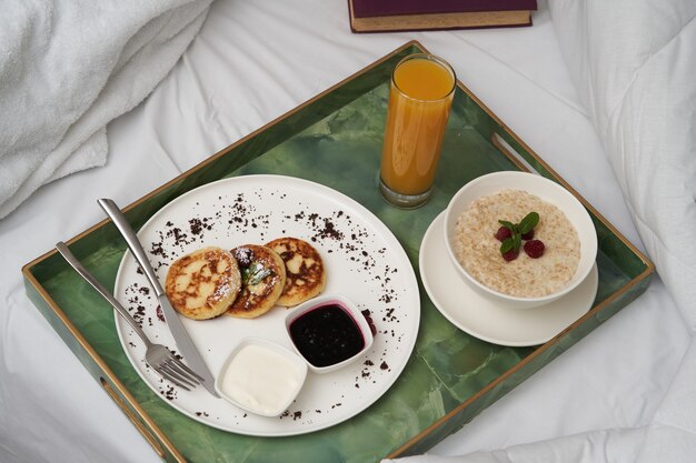 Hotelfrühstück im Bett. Hotel-Service-Frühstück mit frischem Saft, Haferbrei und Pfannkuchen
