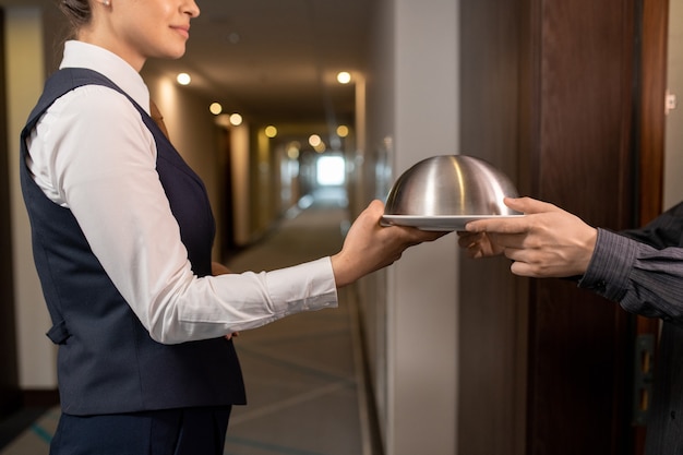 Hotelmanager übergibt Tablett mit Mittagessen an Geschäftsmann