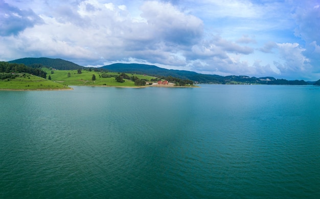 Hotels am Ufer des Sees mit Reflexion der Berge Rhodope gegen bewölkten Himmel Panorama Draufsicht