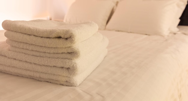 Hotelzimmer Weiße, flauschige, gefaltete Handtücher, Bettwäsche und Kissen auf dem Bett Nahaufnahme