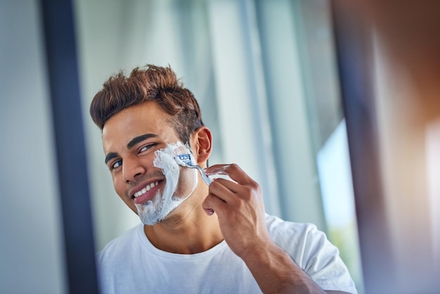 Hoy no barba Disparo de un apuesto joven afeitándose el vello facial en el baño