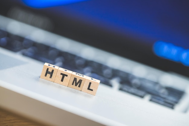 Foto html-websprache holzwürfel mit html-buchstaben, die auf einem laptop-konzept für html liegen