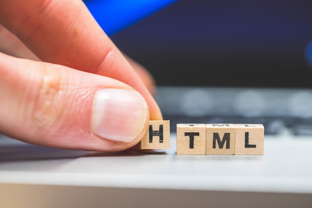 Foto html-websprache holzwürfel mit html-buchstaben, die auf einem laptop-konzept für html liegen