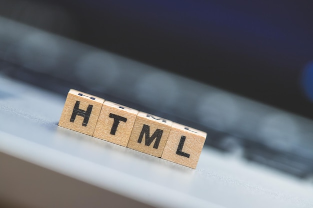 HTML-Websprache Holzwürfel mit HTML-Buchstaben, die auf einem Laptop-Konzept für HTML liegen