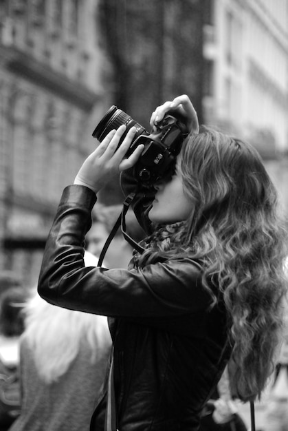 Hubsche junge Fotografin beim Fotografen in der Stadt