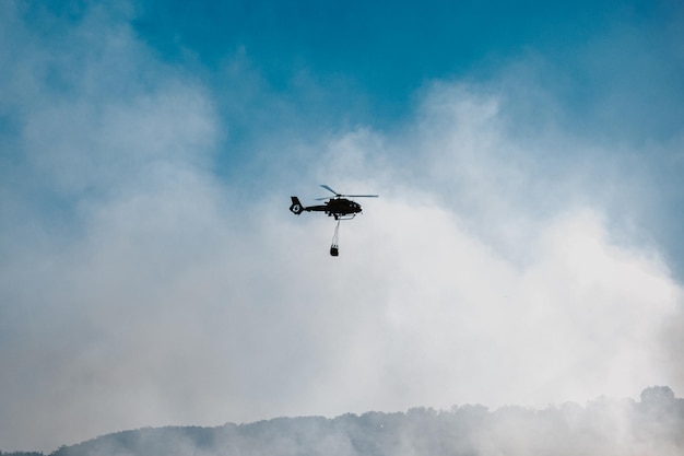 Hubschrauber startet Wasser während eines Waldbrandes