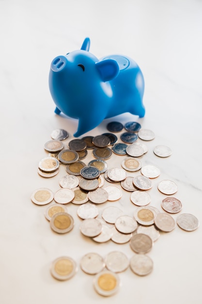 Foto hucha azul colocada sobre una mesa con monedas esparcidas