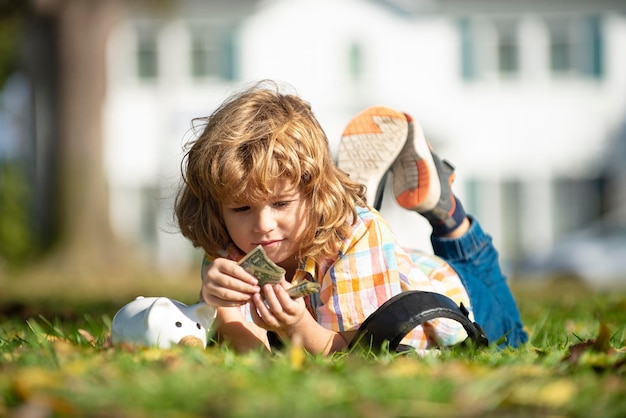 Hucha para dinero niño ahorrando dinero para comprar mantenga rosa hucha tendido en la hierba niño learni