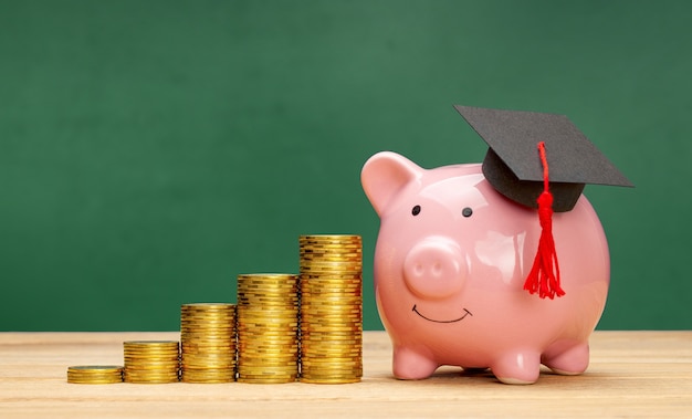 Hucha en una gorra de posgrado cerca de una pila de monedas Ahorros para educación Precios de educación superior