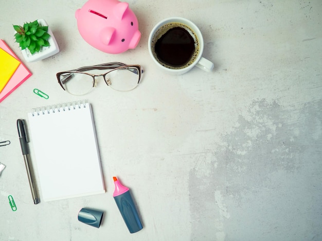 Hucha en la mesa con bloc de notas y gafas