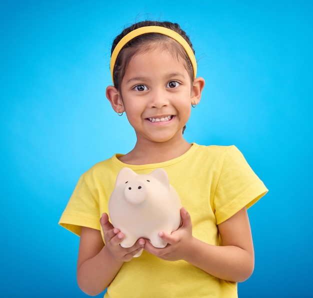 Hucha de retrato facial y niña en estudio aislado en un fondo azul Sonrisa feliz y niño con caja de ahorros o inversión financiera o aprendizaje presupuesto crecimiento financiero o dinero