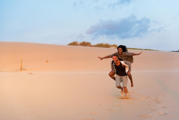 Huckepack lachen und Spaß am Strand haben