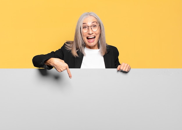 Hübsche ältere Geschäftsfrau mit grauem Haar mit einem Kopienraum, um Ihr Konzept zu platzieren