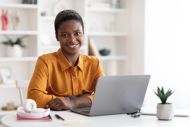 Hübsche afrikanisch-amerikanische Freiberuflerin mit Laptop zu Hause