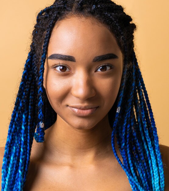 Hübsche afrikanische junge Frau, die in Studiokonzepten über Schönheitskosmetik und Vielfalt posiert