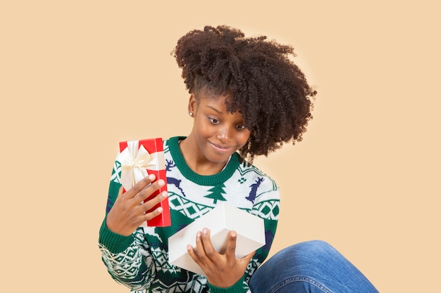 Hübsche afroamerikanische Frau, zu Weihnachten mit Geschenk, beige Hintergrund
