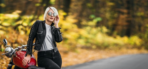 Hübsche blonde Bikerin mit einem roten Motorrad