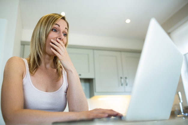 Hübsche blonde Frau, die Laptop betrachtet