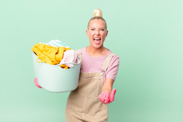 Hübsche blonde Frau, die wütendes, verärgertes und frustriertes Waschkonzept sieht