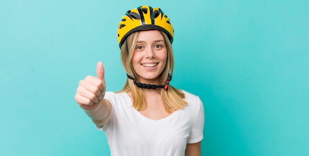 Hübsche blonde Frau fühlt sich stolz und lächelt positiv mit Daumen nach oben Fahrradkonzept
