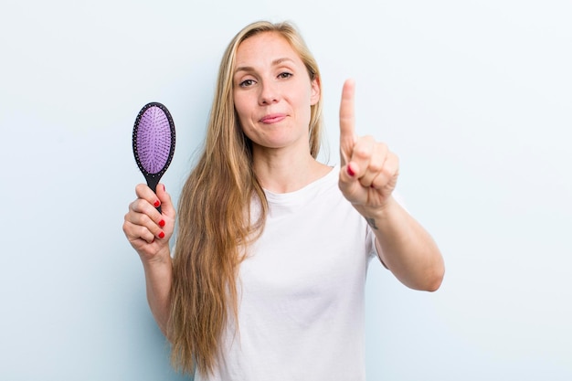 Hübsche blonde junge erwachsene Frau mit einem Haarkamm