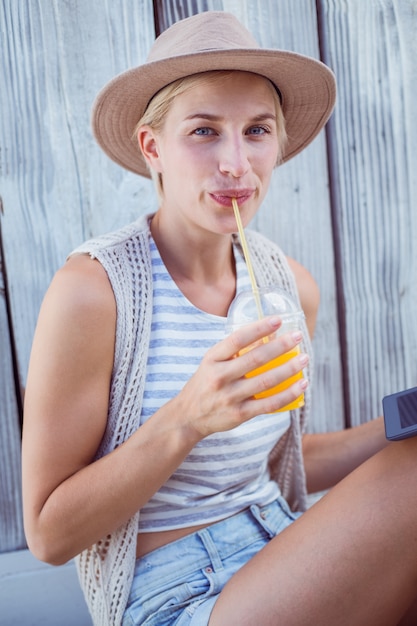 Hübsche Blondine, die ihre Tablette verwenden und Orangensaft trinken