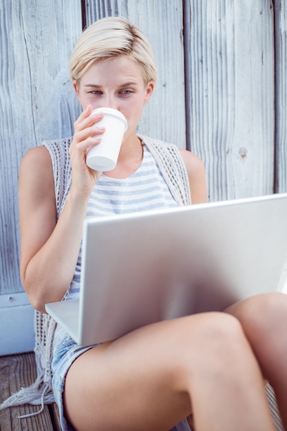 Hübsche Blondine, die ihren Laptop verwenden und Kaffee trinken