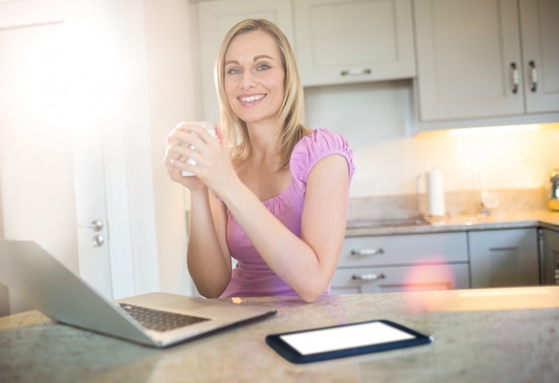 Hübsche Blondine, die Kaffee trinken und Laptop verwenden