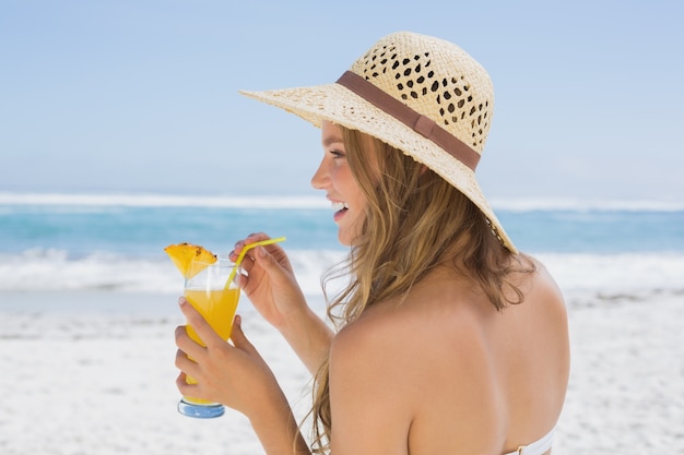 Hübsche Blondine im Bikini, der Cocktail auf dem Strand hält