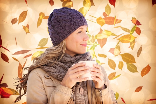 Hübsche Blondine mit Becher vor herbstlichem Blattmuster in warmen Tönen