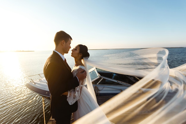 Hübsche Braut und stilvoller Bräutigam zusammen auf Brücke vor dem Hintergrund des Bootes Hochzeit zusammen