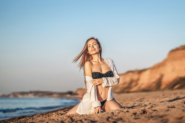 Hübsche brünette Frau, die sich am Strand am Meer entspannt.