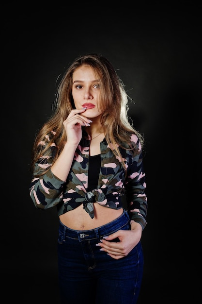 Hübsche brünette Mädchen tragen militärisches Hemd und Jeans und posieren im Studio vor grauem Hintergrund Studio-Model-Portrait