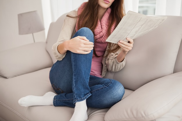 Hübsche Brunettelesezeitung auf Couch