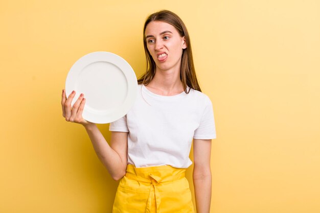 Hübsche Cheffrau des jungen Erwachsenen, die eine leere Platte hält