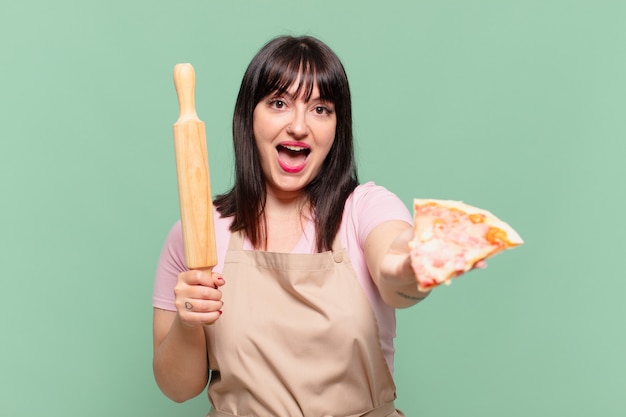 Hübsche Cheffrau überraschten Ausdruck und hält eine Pizza