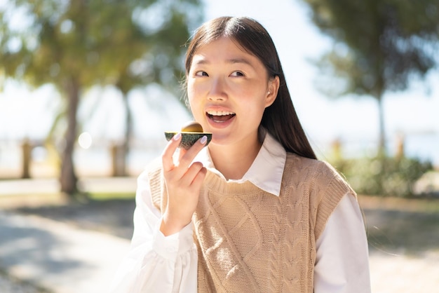 Hübsche Chinesin im Freien mit einer Avocado