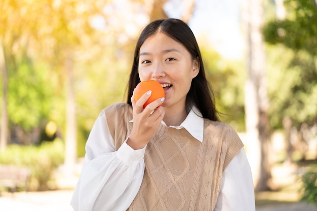 Hübsche Chinesin im Freien mit einer Orange