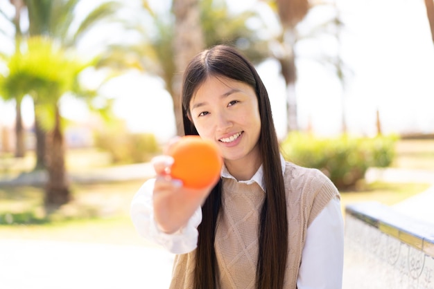 Hübsche Chinesin im Freien mit einer Orange