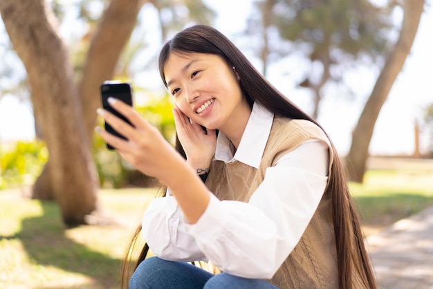 Hübsche Chinesin im Freien mit Handy