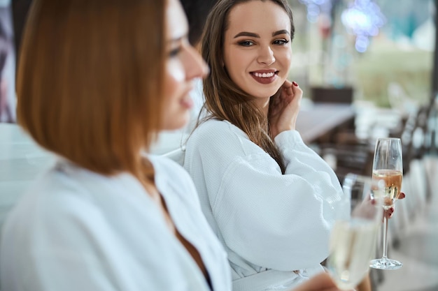 Hübsche Dame, die beim Champagnertrinken Augenkontakt mit einer anderen Dame sucht