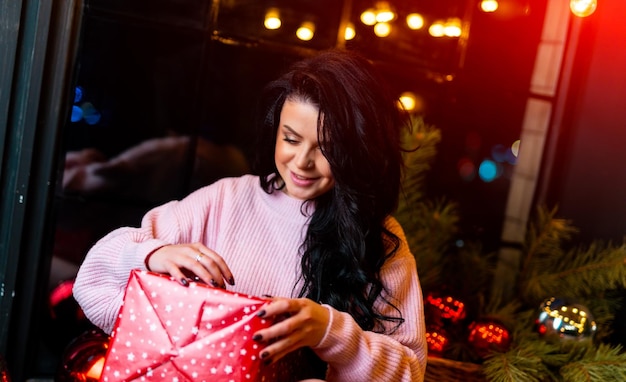 Hübsche Dame in rosa Pullover erhielt an Feiertagen ein Geschenk Glückliche Frau mit Geschenkbox Neujahrsfeierkonzept