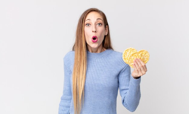 Hübsche dünne Frau, die einen Reisdiätkuchen hält