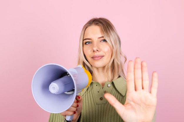 Hübsche europäische Frau im lässigen Pullover auf rosa Wand. unglücklich ernst mit Megaphon, das Stoppschild mit der Handfläche tut