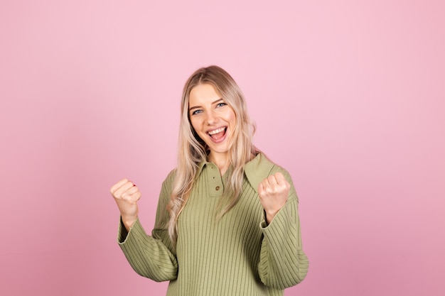 Hübsche europäische Frau im lässigen Strickpullover auf rosa Wand