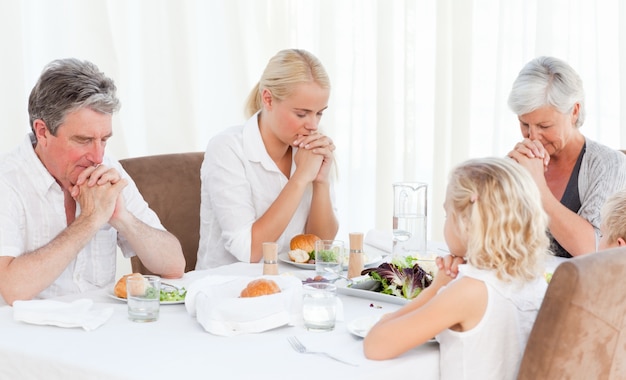 Hübsche Familie, die am Tisch betet