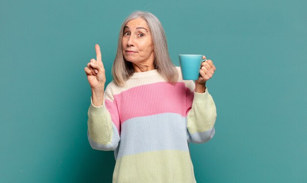 Hübsche Frau des grauen Haares mit einem Kaffee oder einem Tee