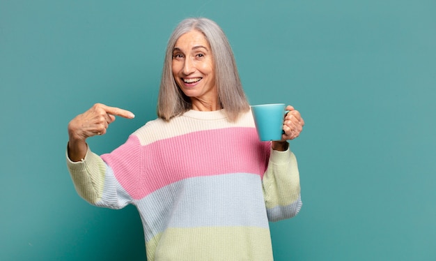 Hübsche Frau des grauen Haares mit einem Kaffee oder einem Tee