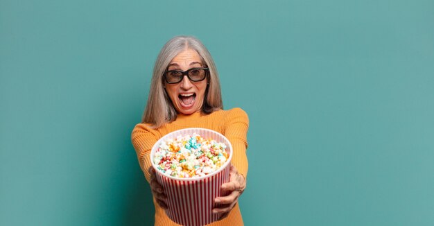 Foto hübsche frau des grauen haares mit einem popcorn-eimer